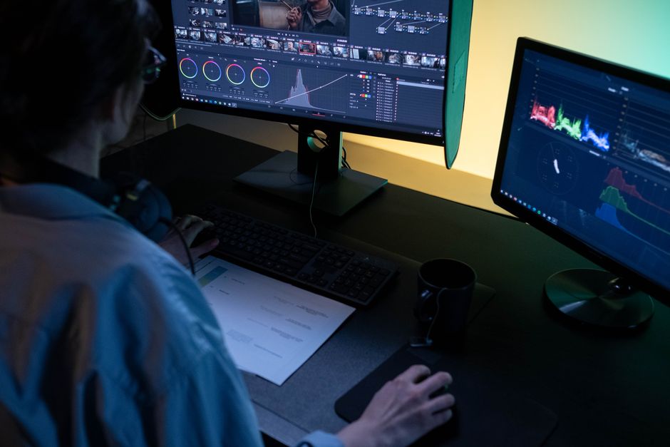 Designer refining curved text generator output in vector software on a desktop monitor